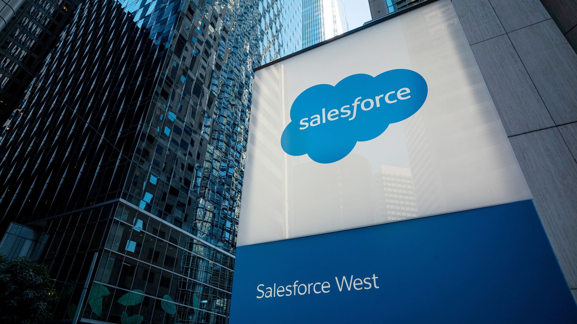 Placa da Salesforce com o logo da nuvem azul e "Salesforce West", em frente a edifícios modernos de vidro.